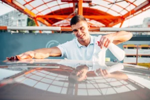 mężczyzna poleruje ręcznie auto na myjni samoobsługowej